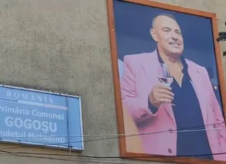 Tabloul fostului primar Jean Rogoveanu, cu un pahar de vin în mână, expus pe fațada Primăriei Gogoșu din Mehedinți, după decesul său anul trecut.